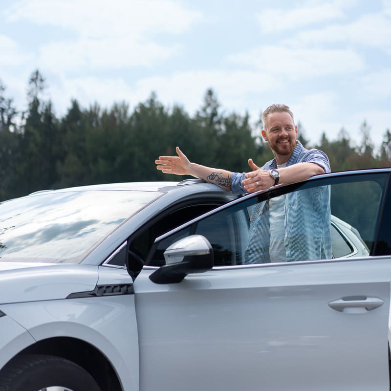 Mies autonsa vieressä iloisena.